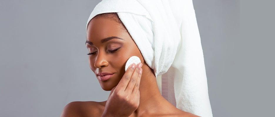 beautiful teen woman wearing towel on her hair while she's applying make up on her face