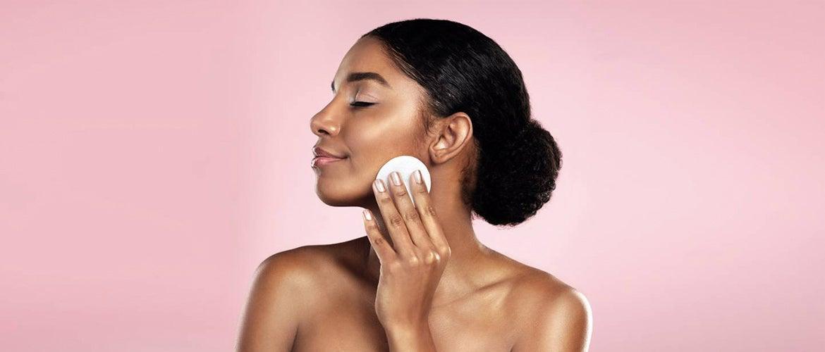 black young woman wiping her face using makeup brush